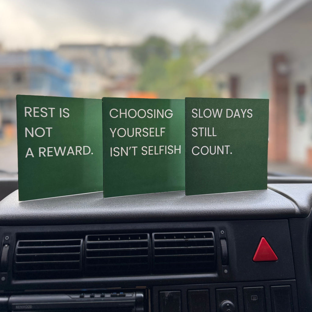 Three green self care art print cards sitting on a car dashboard. 
