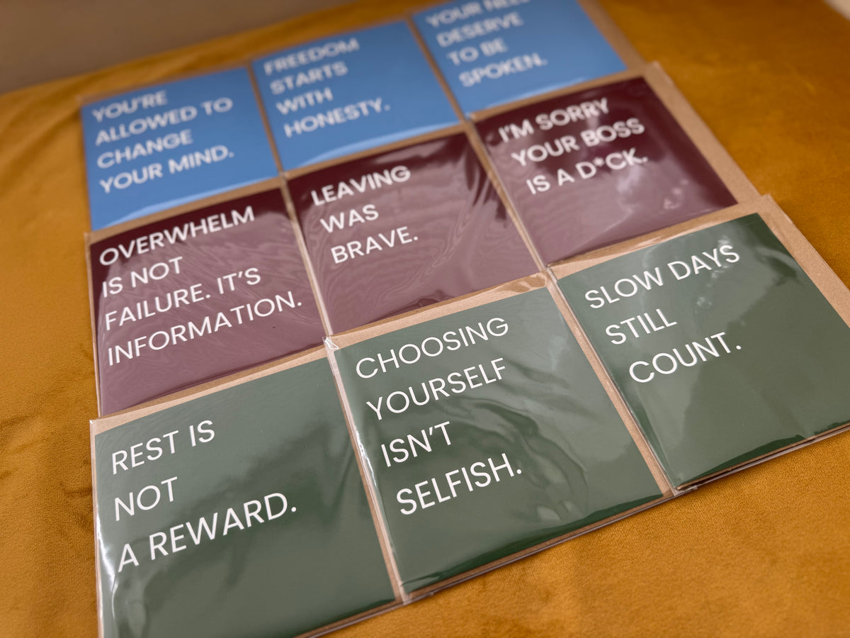 A set of quote cards arranged in a grid on a yellow surface. The cards are wrapped in clear plastic and feature different colours: blue, red, and green, with white text displaying positive affirmations.